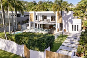 A modern house with a swimming pool, outdoor seating, and lush greenery.
