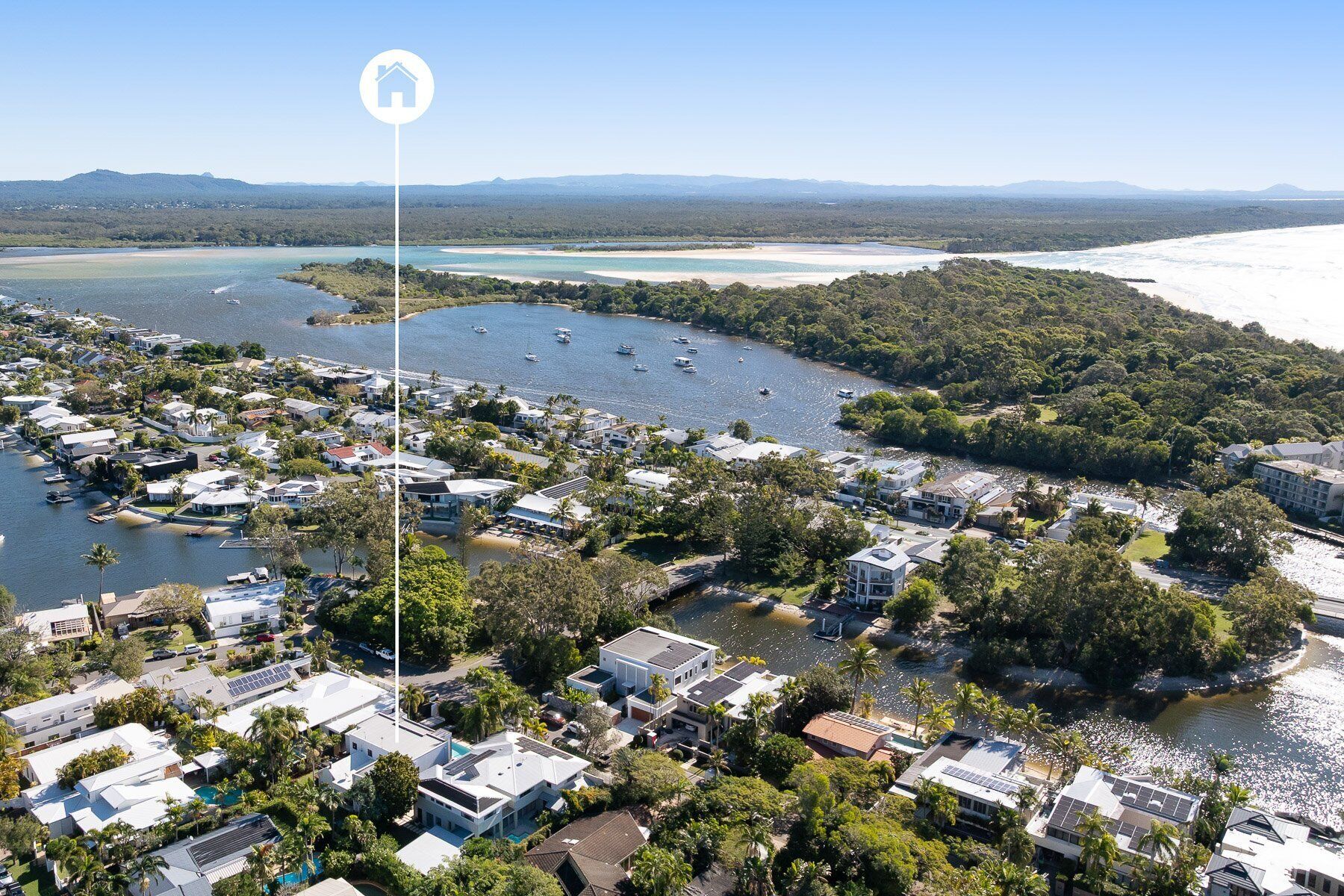 An aerial view of a coastal residential area with houses, boats, and a clear view of the coastline.