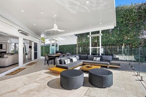 A modern outdoor living space with a sofa, ottomans, and a dining area.