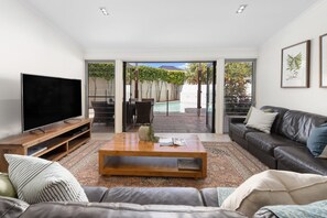 A modern living room with a flat-screen TV, leather sofa, and a coffee table.