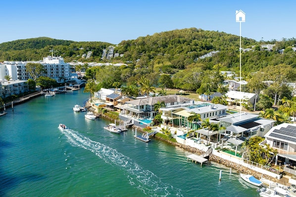 A coastal residential area with houses, a marina, and a hill in the background.