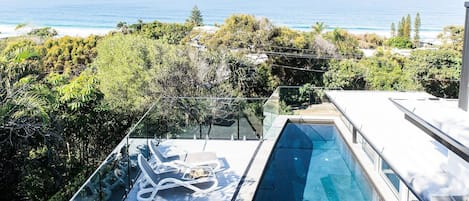 Une piscine sur le toit, dotée de chaises longues et offrant une vue sur l’océan.