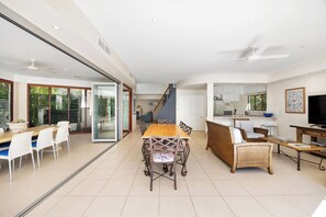 Relax in this open-plan living space with a dining area, comfortable sofa, and kitchen with a large window.