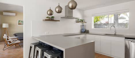 A modern kitchen with a large island, bar stools, a built-in oven, and a window with a view.