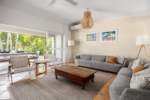 A modern living room with a sofa, armchairs, a coffee table, and a dining area with chairs and a table. There are two framed pictures on the wall, and a hanging light fixture. - Modern Oasis in Noosa Heads (Noosa Heads)