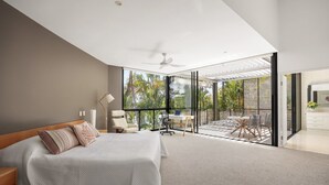 A modern bedroom with a large bed, a desk, and a balcony with a view of greenery. - Luxury Retreat with Private Beach & Jetty (Noosa Heads)