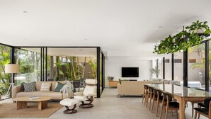 A modern living room with a sofa, coffee table, and dining area with chairs.