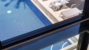 A swimming pool with lounge chairs and a tiled deck area.
