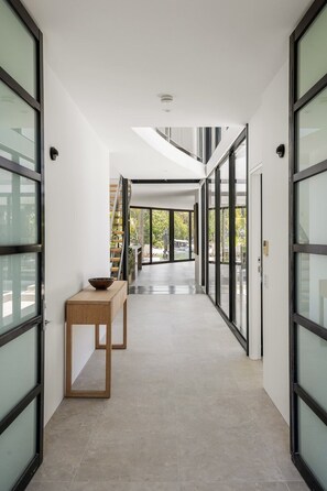A modern hallway with glass doors, a wooden bench, and a view of the outdoors.