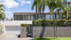 A modern two-story building with a garage, a gated entrance, and a well-maintained lawn.