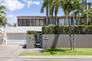 A modern two-story building with a garage, a gated entrance, and a well-maintained lawn. - Luxury Retreat with Private Beach & Jetty (Noosa Heads)
