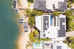 An aerial view of a beachfront property with a pool, umbrellas, and solar panels.