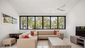 A modern living room with a beige sofa, a coffee table, and a TV.