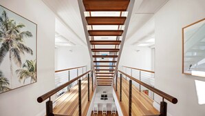 Ein modernes Interieur mit einer Holztreppe, weißen Wänden und Blick auf das Obergeschoss.