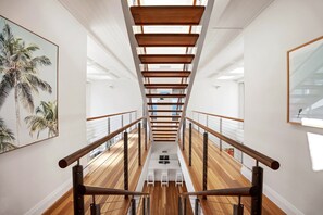 A modern interior with a wooden staircase, white walls, and a view of the upper floor. - The Beach Shack - Getaway on Sunshine Beach (Sunshine Beach)