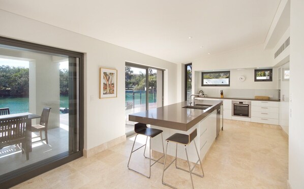 A modern kitchen with a large island, bar stools, and a view of a swimming pool.