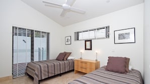 Quarto com duas camas, um penteadeira de madeira e um ventilador de teto.