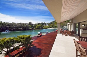 A modern outdoor deck with a view of a river and a boat.