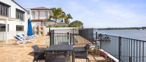 Eine Terrasse mit Gartenmöbeln, einem Pool und Blick auf das Wasser.
