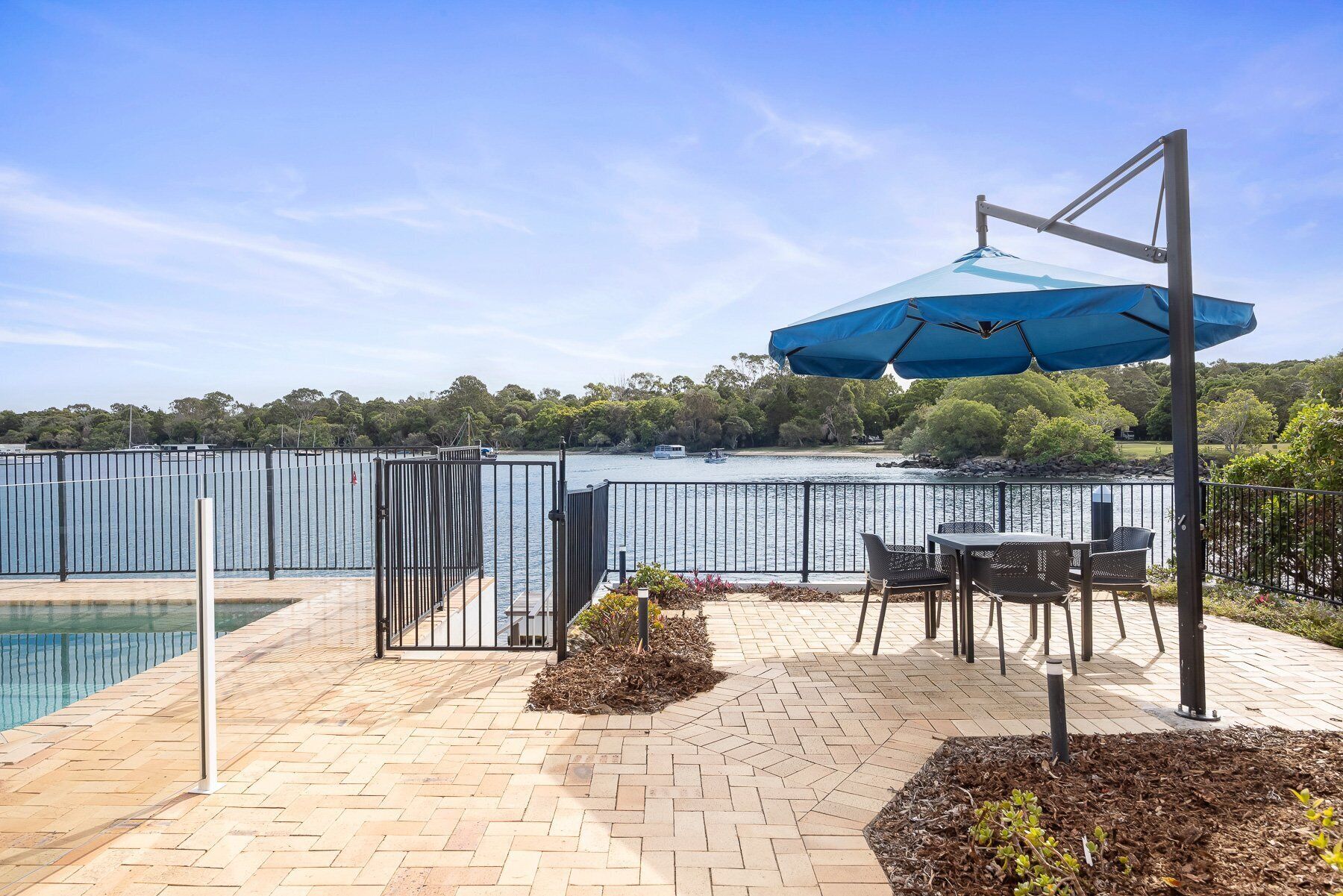 Un patio con piscina, mobiliario exterior y vista al lago.