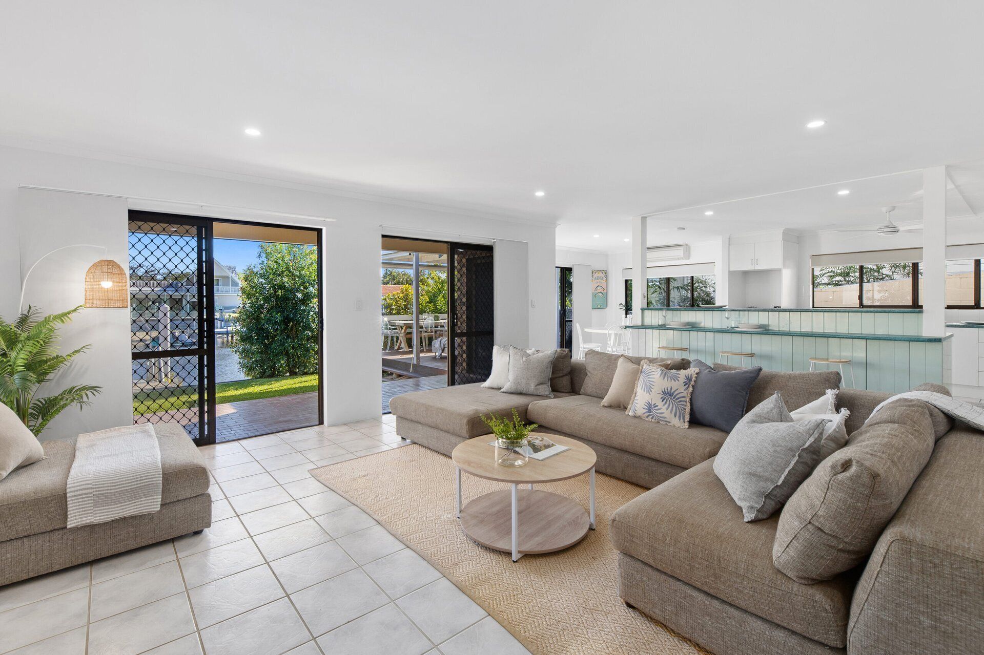 A modern living room with a sofa set, a coffee table, and a view of a pool and outdoor area.