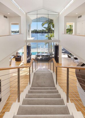 Stunning views of the tropical outdoor setting unfold from the glass-walled staircase, offering a glimpse into the serene surroundings.