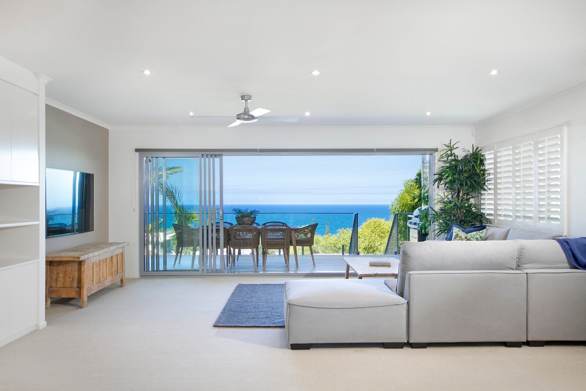 Sala de estar moderna com uma grande porta de vidro deslizante que dá para uma varanda com vista para o oceano.
