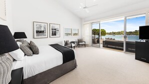 A spacious bedroom with a large bed, a ceiling fan, and a balcony with a view of the water. - Luxury Riverfront: Private Pool, Water Views (Noosa Heads)