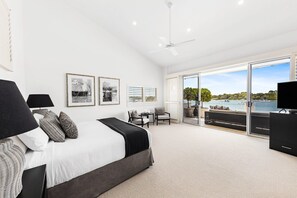 A spacious bedroom with a large bed, a ceiling fan, and a balcony with a view of the water. - Luxury Riverfront: Private Pool, Water Views (Noosa Heads)