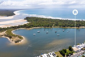 An aerial view of a coastal area with boats, a beach, and a residential area with houses.
