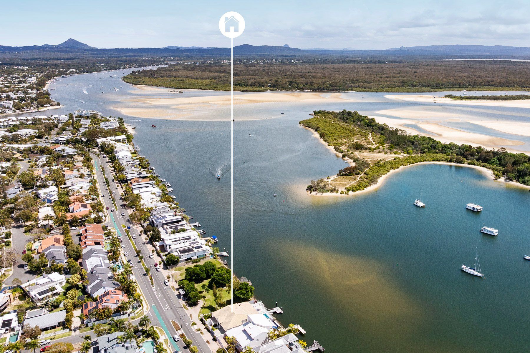 An aerial view of a coastal area with residential buildings, a marina, and a bay.