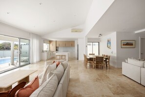 A modern interior with a dining area, kitchen, and a view of a pool.