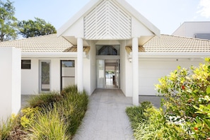 A modern two-story house with a tiled roof, a covered entrance, and a visible garage door. - The River Rest - Noosa Jetty Stay (Noosa Heads)