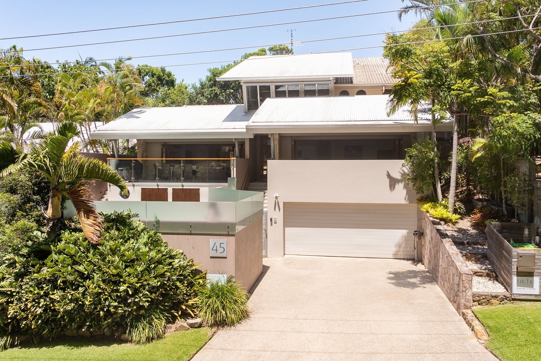 A two-story house with a garage, surrounded by lush greenery and a well-maintained lawn.
