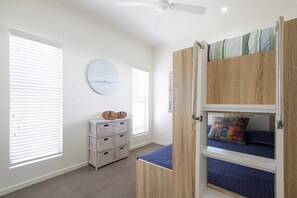 A room with a bunk bed, a ceiling fan, and a wall-mounted circular decoration.