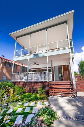 A two-story building with a balcony, a covered patio, and a front entrance.