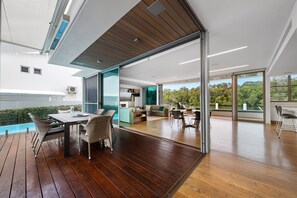 Enjoy a seamless transition between indoor and outdoor living spaces, featuring a dining area, comfortable seating, and a kitchen with modern appliances.
