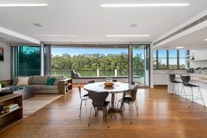 Relax in this open-plan living space with a large dining table, comfortable sofa, and stunning views of the lush landscape.