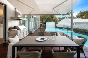 Un espace extérieur aménagé pour prendre les repas, avec une table, des chaises et une vue sur une piscine.