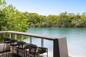 A balcony with a view of a calm lake surrounded by dense greenery.