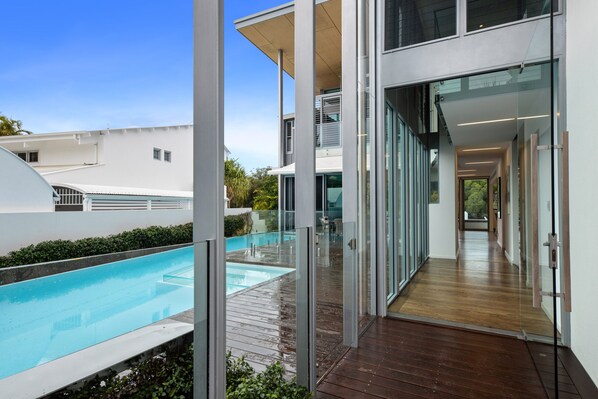 Experience a comfortable and stylish living experience with a spacious open-plan living area, outdoor pool, and sleek entryway.