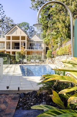 Una casa moderna con piscina, rodeada de exuberante vegetación y una cascada.