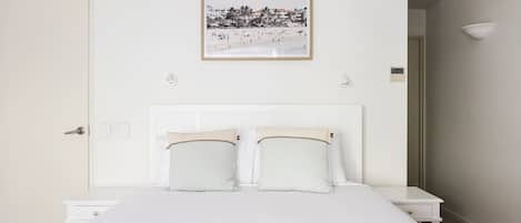 Una camera da letto con un letto, un comodino, un quadro appeso al muro e una porta.
