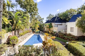 A residential area with a swimming pool, stone walls, and lush greenery.