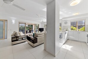 Relax in a spacious living area with a sofa set and flat-screen TV, and enjoy a view of the surrounding greenery from the kitchen window.