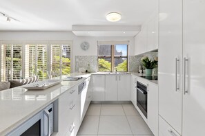 A modern kitchen with white cabinetry, a built-in oven, and a window with a view of greenery.