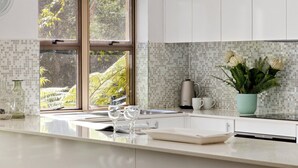 Una cocina moderna con un ventanal grande, armarios blancos y salpicadero de azulejos.