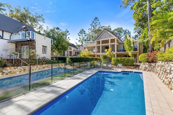 A residential area with a swimming pool, stone walls, and various houses.