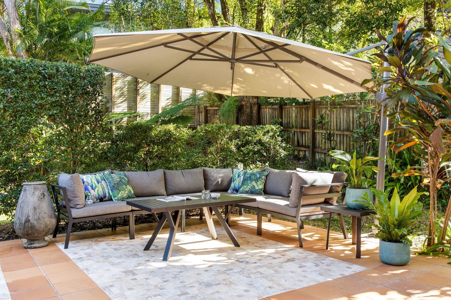 An outdoor seating area with a sectional sofa, a table, and a large umbrella.