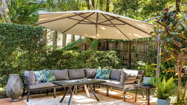 Un espacio al aire libre con un sofá modular, una mesa y una sombrilla grande.